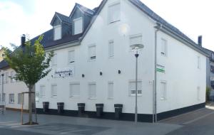 a large white building with a tree in front of it at Boardinghouse Apart-Hotel in Oberkochen