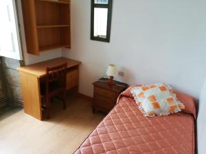a bedroom with a desk and a bed and a table at Pensión Residencia Universitaria Rey in Santiago de Compostela