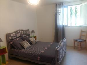 een slaapkamer met een bed met kussens en een raam bij les oliviers in Carpentras