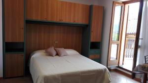 Schlafzimmer mit einem Bett mit einem Kopfteil aus Holz in der Unterkunft Sweet Home Casa Vacanze "La Terrazza" in Rovetta