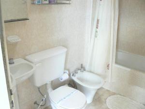 ein weißes Badezimmer mit Toilette und Waschbecken in der Unterkunft Departamentos Santa Monica in Puerto Madryn + 25 Fotos