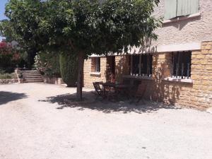 a table and chairs under a tree next to a building at les oliviers in Carpentras