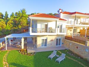 una grande casa bianca con sedie in cortile di Paliouri Sea Lounge by Luxlikehome a Paliouri