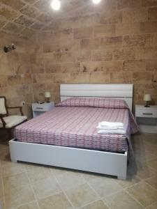 a bedroom with a bed and two tables and a chair at Corte Della Luna in Acquarica del Capo