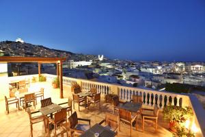 a balcony with tables and chairs and a view of a city at Aegli in Ermoupoli