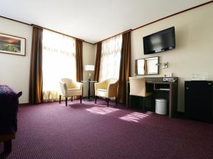 Habitación de hotel con escritorio, sillas y TV. en Hotel Faber en Hoogezand
