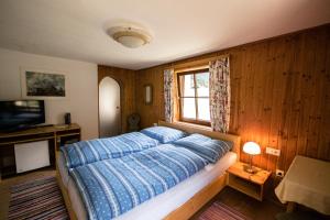 ein Schlafzimmer mit einem Bett mit blauer Decke und einem Fenster in der Unterkunft Pirschenhof in Gschnitz