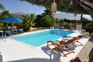 a swimming pool with two chairs and a umbrella at Casa Silca in Marbella