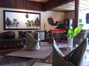 uma sala de estar com cadeiras e uma mesa com um ecrã em Harmony Inn em Yogyakarta