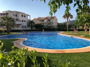 a large swimming pool in a yard with buildings in the background at Ático en el mar in Alcossebre +28 photos