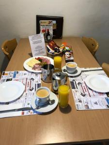a table with plates and cups of coffee and newspapers at Hotel Restaurant Simplon in Frutigen