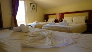 una camera d'albergo con tre letti con lenzuola bianche di Hotel Veli a Sarandë