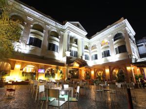 a hotel with tables and chairs in a courtyard at night at Kiss Gardenhome Chic Hotel in Hat Yai
