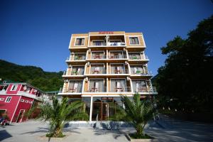a hotel building with palm trees in front of it at Medea Kvariati in Kvariati