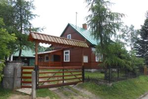 a red house with a gate and a fence at Agroturystyka U Jadwigi Lipsk in Lipsk