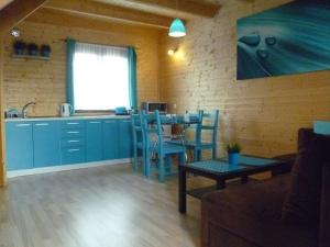 uma cozinha com armários azuis e uma mesa com cadeiras em Tęczowe Domki em Władysławowo