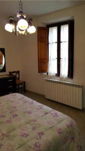 1 dormitorio con cama, ventana y lámpara de araña en Locanda il Cacciatore, en Pari