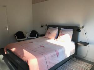 a bedroom with a bed with pink sheets and two chairs at Bij Zelle in Garderen