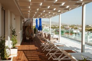 een balkon met ligstoelen en blauwe parasols bij Scale Suites in Athene