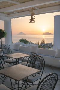un patio con tavoli, sedie e vista sull'oceano di B&B Le Sette Vele Da Riccardo a Santa Marina Salina