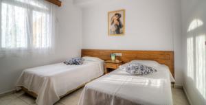 two beds in a room with white walls and a window at Elia & Tina Apartments in Hersonissos