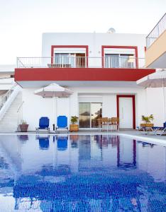 una casa con piscina con sedie e ombrelloni di Gennadi Gardens exclusive apartments a Gennadi