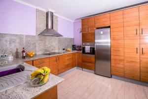 a kitchen with wooden cabinets and a stainless steel refrigerator at Fully Airconditioned Costa Blanca Pool House with Superb Views Over the Orba Valley, Sleeps 12 in Benimeli