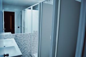 un bagno con doccia in vetro e lavandino di Corujinha Hostel a Lisbona