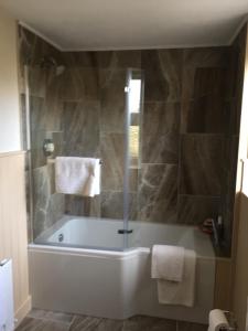 a bathroom with a bath tub with a glass door at Mill Cottages in Kesh