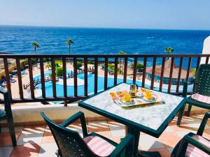 una mesa y sillas en un balcón con vistas al océano en Rocas del Mar, en Costa del Silencio