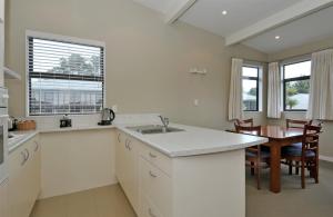 a kitchen with a sink and a table in it at Aotea Lodge Porirua in Porirua