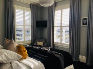 a bedroom with a bed and two windows at Franklin38 in Auckland