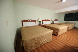 two beds in a hotel room with wood floors at Texas Inn Waxahachie in Waxahachie
