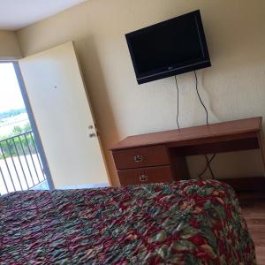 a bedroom with a bed and a tv on the wall at Country Host Inn in Texarkana