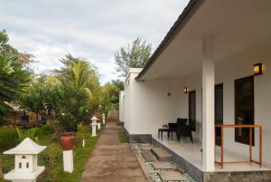 a white house with a pathway next to a yard at Blue Marine Resort in Gili Air