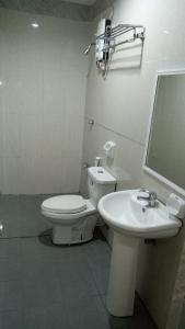 a white bathroom with a toilet and a sink at Jeamco Royal Hotel-Cotabato in Cotabato