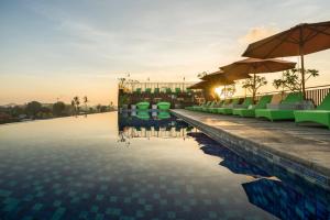 Zest Legian by Swiss-Belhotel International في ليغِيان: مسبح فيه كراسي ومظلات على المنتجع