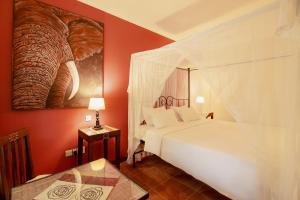 1 dormitorio con cama blanca y mesa en Mediterraneo Boutique Hotel en Dar es Salaam