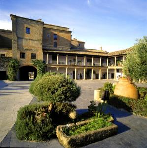 an old building with a courtyard with trees and bushes at Parador de Oropesa in Oropesa