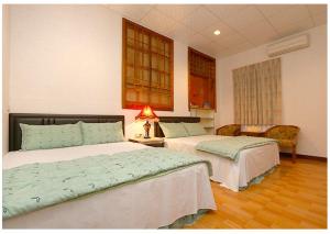 Un dormitorio con dos camas y una mesa con lámpara. en 初鹿敦親牧鄰民宿, en Chulu
