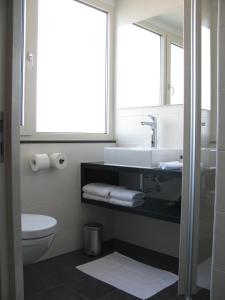 La salle de bains est pourvue d'un lavabo, de toilettes et d'un miroir. dans l'établissement Boutique Hotel de Zwaluw, à De Koog