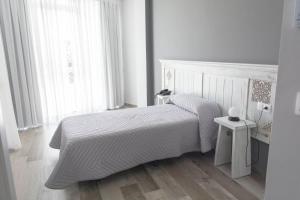 a white bedroom with a bed and a window at Hotel Mica in Palas de Rei