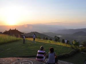 姆杜克的住宿－Puri Lumbung Cottages Restaurant & Spa Munduk，一群坐在山丘上观看日落的人