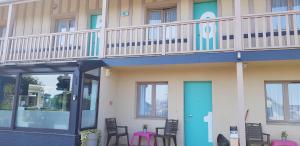 a building with a balcony with a blue door and chairs at Hôtel L'ideal le Mountbatten in Arromanches-les-Bains