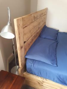 a bed with a wooden headboard next to a table at Ty Glyndwr Bunkhouse, Bar and cafe in Caernarfon