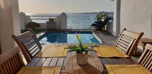 a patio with a table and chairs and a swimming pool at Westbank Private Beach Villa, 4 Bedrooms, Private pool, on the Beach! in Gordonʼs Bay