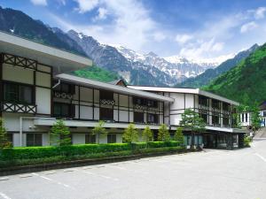 un edificio con un parcheggio di fronte alle montagne di Hotel Hotaka a Takayama