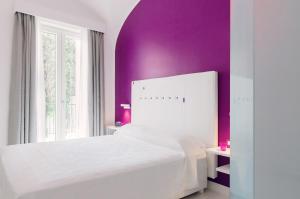 a bedroom with a white bed and purple walls at Ravello In in Ravello