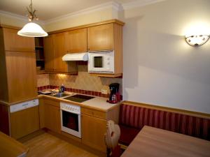 een kleine keuken met houten kasten en een magnetron bij Appartement Haus Seer in Wagrain