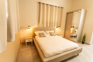 a bedroom with a white bed and a mirror at Eshel Mansion - Boutique Suites in Beer Sheva
